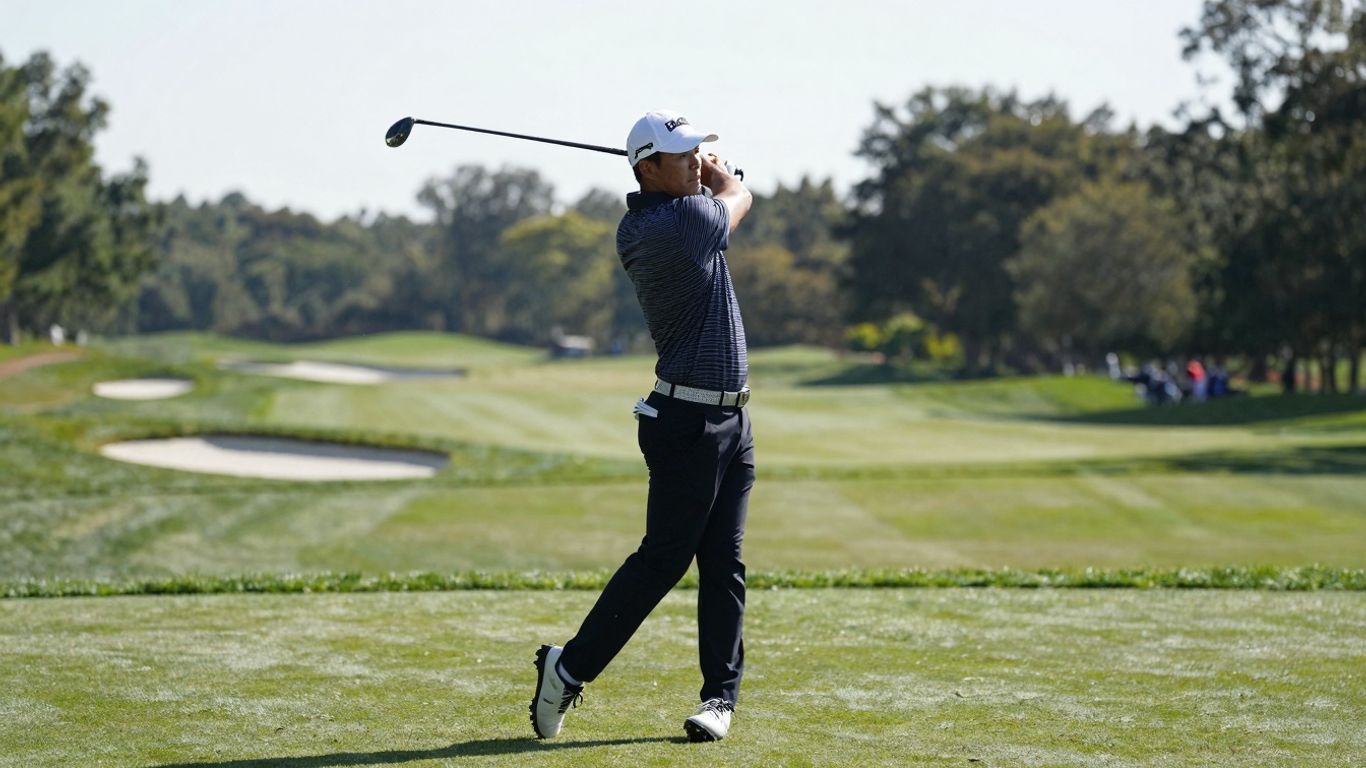 Golfer Tom Kim swings his club on a sunny golf course.