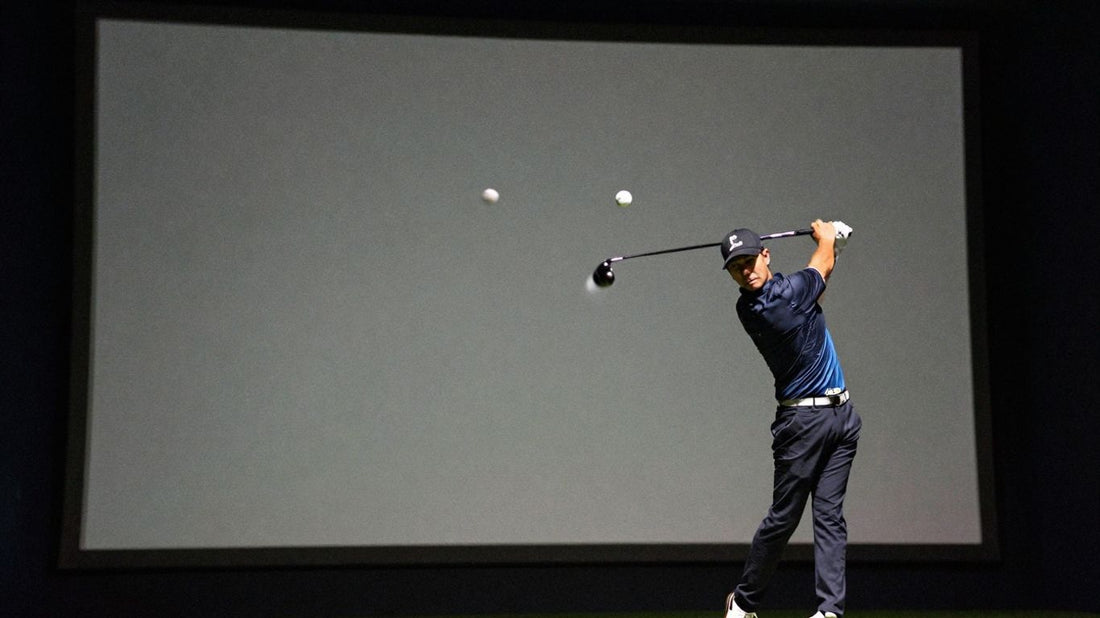 Golfer hitting a ball towards a glowing screen.